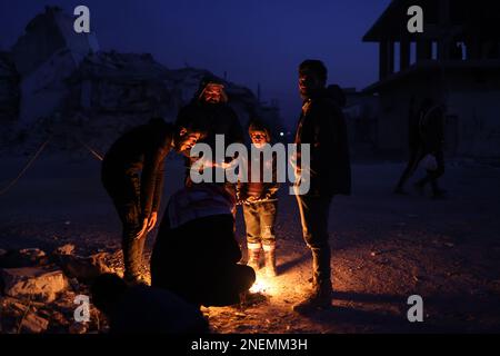 Jindires, Syrien. 16. Februar 2023. Die Syrer wärmen sich neben den Trümmern ihres Hauses auf, das durch das Erdbeben zerstört wurde, das die türkisch-syrische Grenze durchbrach. Kredit: Anas Alkharboutli/dpa/Alamy Live News Stockfoto