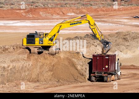Ein HD-Hydraulikbagger beladen einen Containerwagen mit gefährlichen Uranbergwerken im UMTRA-Sanierungsprojekt in Moab, Utah. Stockfoto