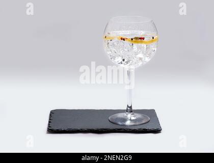 Glas Gin und Tonic auf Schieferteller mit weißem Hintergrund Stockfoto