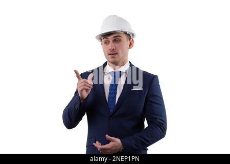 Ein gutaussehender Mann im Anzug und Helm zeigt Emotionen beim Lösen von Problemen, indem er mit dem Zeigefinger zeigt. Konzept im Studio auf weißem Hintergrund. Stockfoto