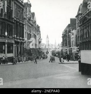 London, England. 1953. Blick auf Whitehall von der Ecke Charing Cross. Viele der Gebäude sind mit Bannern und Flaggen versehen, insbesondere für die Krönung von Königin Elizabeth II., die am 2. Juni 1953 stattfand. In der Ferne sind die Straßendekorationen der „permanenten Wächter“ sichtbar, die von Sir Hugh Maxwell Casson entworfen wurden, und die große Uhr von Westminster, besser bekannt als Big Ben. Stockfoto