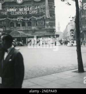 London, England. 1953. Blick auf das Palace Theatre im Londoner West End von der Kreuzung Charing Cross Road und Cambridge Circus. Das Theater wurde mit einem großen Königlichen Zypher und künstlichen Bändern dekoriert, insbesondere für die Krönung von Königin Elizabeth II., die am 2. Juni 1953 stattfand. Im Theater wird das Musical „The Glorious Days“ mit Anna Neagle gezeigt. In der Ferne ist die St. Anne's Church in Soho zu sehen. Stockfoto