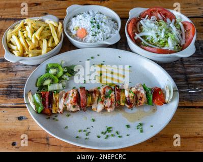 Gemischtes gegrilltes Fleisch auf einem Teller mit Gemüsesalat, Reiskartoffeln, Cusida. Traditionelles Essen. Spieß Stockfoto