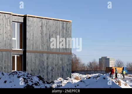 Holzfassade eines freistehenden modularen Hauses mit Fenstern auf dem Hintergrund des Bauwerks Stockfoto