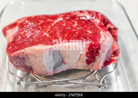 Makro-Nahaufnahme von entbeintem New Yorker Steak-Rindfleisch dickes Fleisch in einer Glaspfanne zum Rösten vor dem Grillen mit saftiger Konsistenz Stockfoto