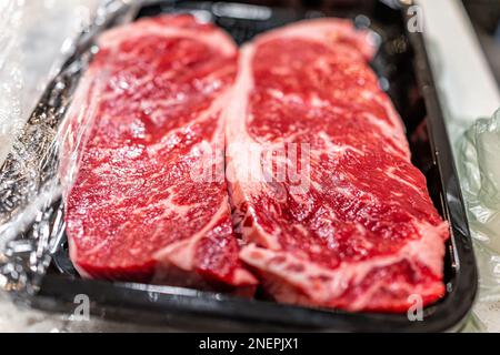 Zwei rohe Steaks aus rohem rotem Streifen Teilstücke von Fleischverschlussmakros von Texturmetzger, geschnitten auf Plastiktablett in der Küche Stockfoto