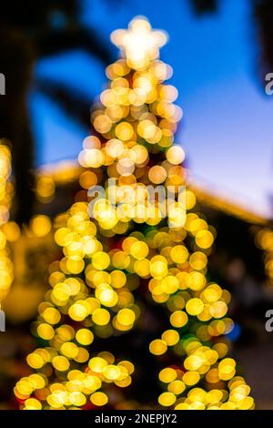 Unschärfe-Bokeh-Lichter in Neapel. Florida Downtown Third Street South in der Abendnacht und Weihnachtsbaum Weihnachtsdekorationen und Ornamente Stockfoto