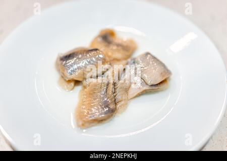Eingelegte, wild gefangene Heringsteile Makrozusammenfassung mit Textur von Filets auf weißem Plattenstudio, das als traditionelles osteuropäisches Essen aufgenommen wurde Stockfoto