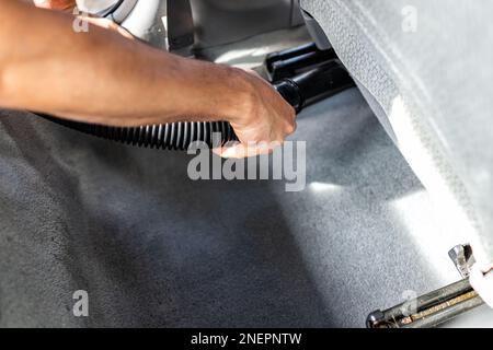 Staubsauger an der Autowaschanlage, Mann reinigt den Teppichboden des Fahrzeugs mit Innenschließung an der Selbstbedienungsstation, entfernt Schmutzstaub Stockfoto