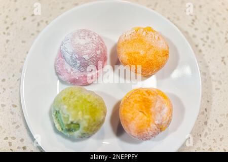 Eis Mochi Daifuku Dessert, süßes japanisches Essen auf weißem Teller Makro-Nahaufnahme von vier gefrorenen gefüllten Reiskuchen mit grünem Tee Matcha, erdbeermann Stockfoto