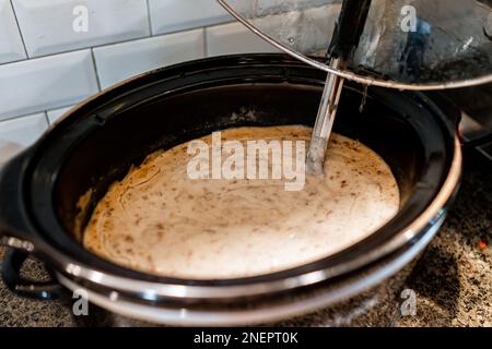 Langsam gekochte Wurstsoße im Herd mit Kelle frisch zubereitete warme Speisen am Morgen im Hotel, kontinentales kostenloses Frühstück für Biscuits in Bankettkantine Restur Stockfoto