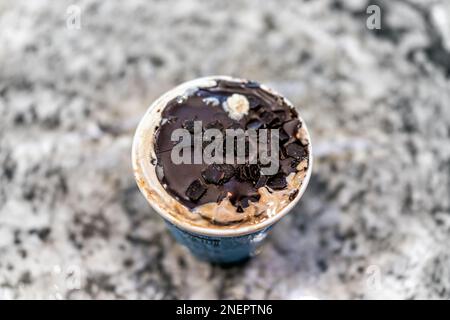 Gefrorenes Eis mit Schokoladen-Ganache auf einem gewöhnlichen Pint-Tubenbehälter auf dem Küchentisch Bokeh-Hintergrund mit Konsistenz von Keksbrownie p Stockfoto