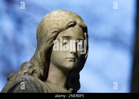 Wunderschöne Statue einer jungen Frau mit traurigem Blick auf den Boden auf einem Friedhof Stockfoto