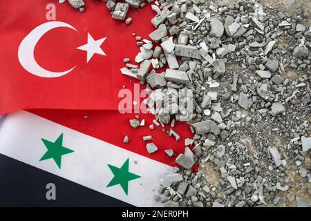 Erdbeben in der Türkei und in Syrien, Hintergrund der türkischen und syrischen Flagge und Ziegeltrümmer Stockfoto