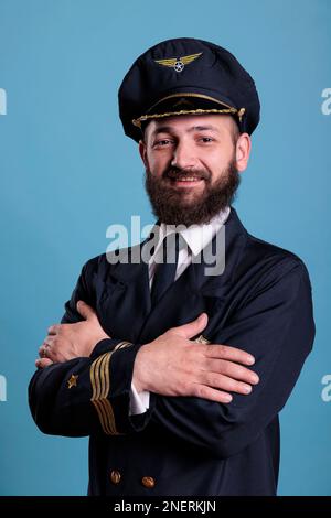 Flugzeugflieger steht in professionellem, einheitlichem Porträt, selbstbewusster Flugzeugkapitän steht, schaut in die Kamera, Studio mittlere Aufnahme, Seitenansicht. Zivilpilot mit Abzeichen auf der Jacke Stockfoto