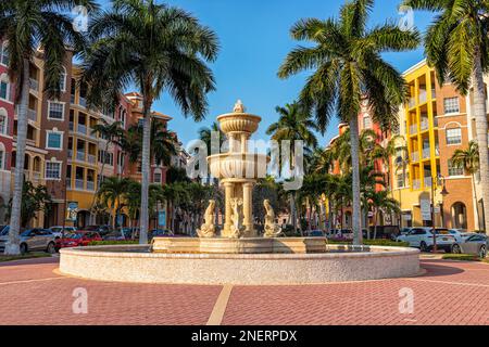 Naples, USA - 29. Januar 2021: Florida Bayfront Wohnstraße Wohnanlagen farbenfrohe mehrfarbige Gebäude mit Springbrunnen von Palmen und Stockfoto