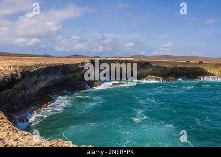 Herrlicher Blick auf die felsige Küste, wo große türkisfarbene Wellen des Atlantischen Ozeans auf Felsen brechen. Aruba. Stockfoto