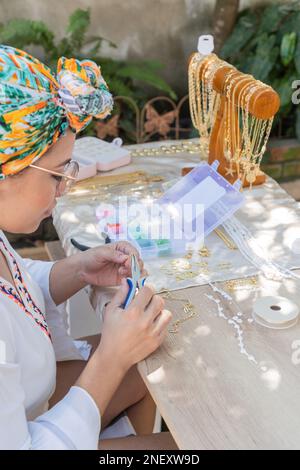 Frauen machen Halsketten auf rustikalen Holztischen Stockfoto