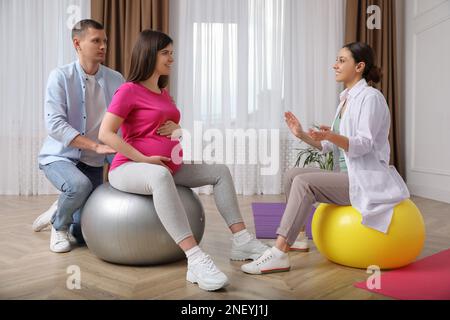 Schwangere Frau mit Ehemann und Hebamme im Fitnessstudio Stockfoto