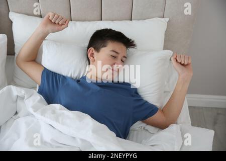 Süßer Teenager, der sich zu Hause im Bett streckt Stockfoto