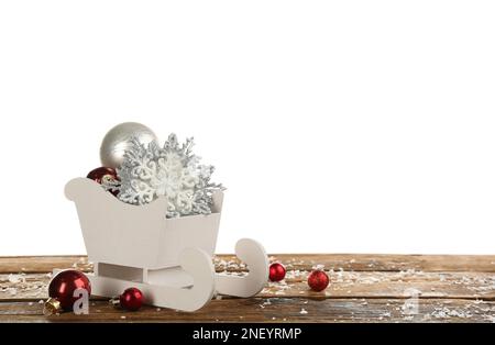 Dekorativer Schlitten mit Weihnachtsschmuck auf Holztisch. Platz für Text Stockfoto