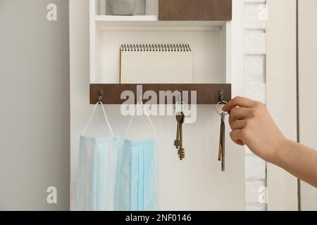 Eine Frau, die die Schlüssel vom Kleiderbügel im Flur nimmt, Nahaufnahme Stockfoto