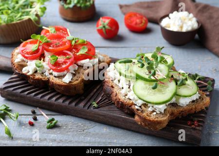 Köstliche Sandwiches mit Gemüse, Käse und Mikrogreens auf grauem Holztisch Stockfoto