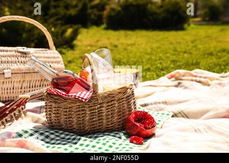 Köstliche Speisen und Weine im Picknickkorb auf der Decke im Freien. Platz für Text Stockfoto