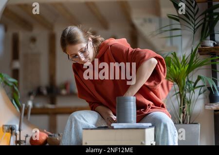 Töpferkünstlerin Frau aus Keramikladen, die in einer modernen Werkstatt formende Lehmvase oder Gläser herstellt. Stockfoto