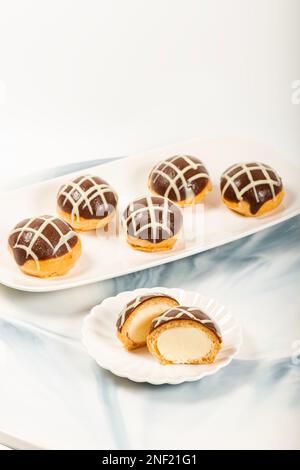 Sechs Packungen glutenfreie Profiteroles mit Milch und weißer Schokolade gefüllt mit frischer Sahne. Stockfoto