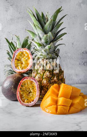 Verschiedene Früchte, Ananas, Mango und Passionsfrüchte. Thailändische Früchte auf einem hellen Tisch im Sonnenlicht Stockfoto