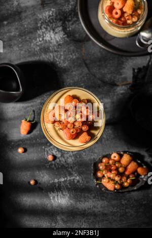 panna Cotta auf dunklem Hintergrund. panna Cotta mit Himbeeren und Johannisbeeren Stockfoto