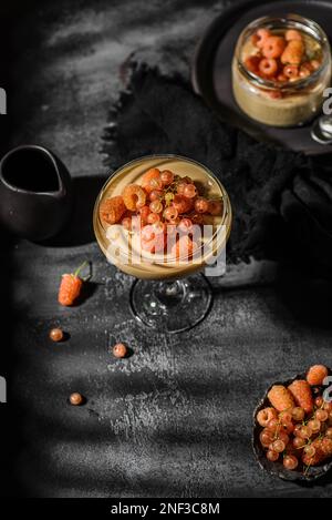 panna Cotta auf dunklem Hintergrund. panna Cotta mit Himbeeren und Johannisbeeren Stockfoto