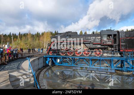 RUSKEALA, RUSSLAND - 09. OKTOBER 2022: Touristen beobachten, wie sich eine Dampflokomotive an einem Oktobernachmittag auf dem Drehteller dreht Stockfoto