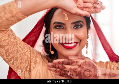 Wir können ihre Schönheit auch nicht aus den Augen lassen. Porträt einer wunderschönen jungen Frau, die ihr Gesicht mit den Händen am Hochzeitstag bedeckt. Stockfoto