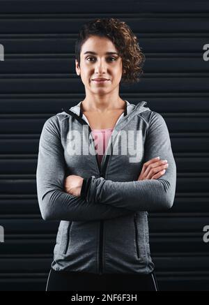 Bereit für das Training. Verkürztes Porträt einer attraktiven jungen Frau, die vor dem Training in ihrer Trainingskleidung vor schwarzem Hintergrund steht. Stockfoto