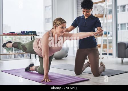 Gleichgewicht ist der Schlüssel zu allem im Leben. Ganzkörperaufnahme einer erwachsenen Frau, die mit ihrem Physiotherapeuten in einer Sport- und Bewegungsübungen macht Stockfoto