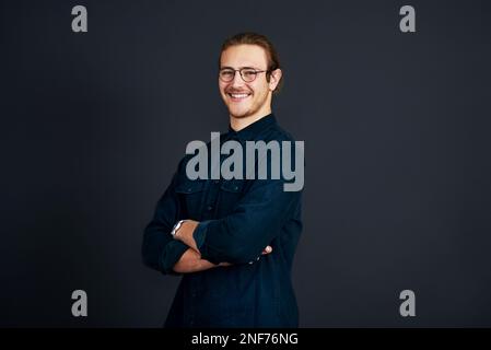 Ein Leben zu führen, das ich wählen muss. Verkürztes Porträt eines gutaussehenden jungen Geschäftsmannes, der allein mit gefalteten Armen vor einem schwarzen Hintergrund im steht Stockfoto