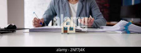 Person Hand Tun Immobilien Steuerberechnung Mit Rechner Des Hauses Modell Stockfoto