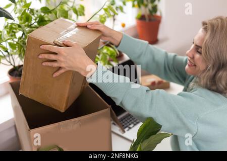 Nahaufnahme eines weiblichen Online-Shops, Inhaber eines kleinen Unternehmens, Unternehmer, der Verpackungspakete nach dem Versand vorbereiteter Versandkarton auf dem Tisch vorbereitet Stockfoto