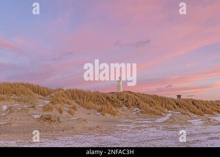 Panoramablick über die Dünen und den Leuchtturm des dänischen Küstenorts Blavand bei Sonnenaufgang an einem eisigen Wintertag Stockfoto