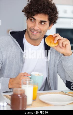 Ein hübscher Mann, der beim Frühstück lächelt Stockfoto