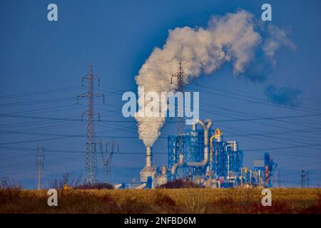 Industrielle Szene mit Schornstein, Silos, Holzhaufen und Rauch am stürmischen Himmel. Holzindustrie. Möbelfabrik. Stockfoto