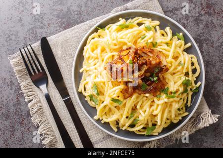 Kasespatzle leckere Nudeln mit Käse und gebratenen Zwiebeln aus nächster Nähe auf einem Teller auf dem Tisch. Horizontale Draufsicht von oben Stockfoto