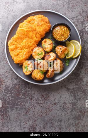 Die Münchner Schnitzel-Kalbskoteletts werden mit einer Kombination aus süßem Senf und Meerrettich gebürstet, anschließend mit Mehl, Eiern und Brotkrumen bestrichen und anschließend mit Pommes frites frittiert Stockfoto