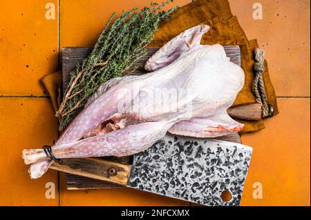 Farm Rohe Guineafowl, Perlhühner mit Kräutern zum Kochen. Orangefarbener Hintergrund. Draufsicht. Stockfoto