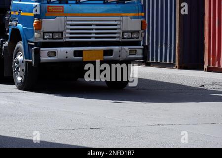 LKWs in einem Logistikgelände mit im Hintergrund gestapelten Containern. Stockfoto