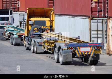 LKWs in einem Logistikgelände mit im Hintergrund gestapelten Containern. Stockfoto