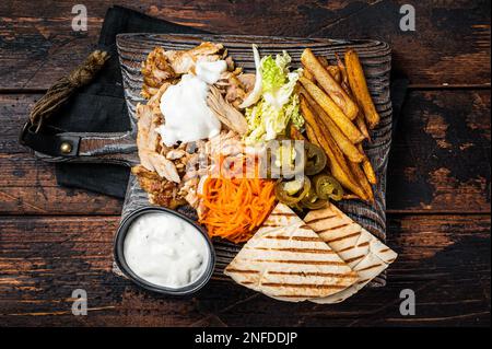 Kebab, Shawarma, gegrilltes Gyro-Fleisch mit pommes und Gemüse auf einem Holzbrett. Holzhintergrund. Draufsicht. Stockfoto