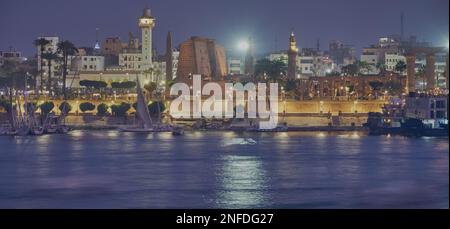 Luxor, Ägypten Nachtaufnahme vom Westufer aus, der den Nil mit Felukken und den Luxor Tempel im Ostufer zeigt Stockfoto